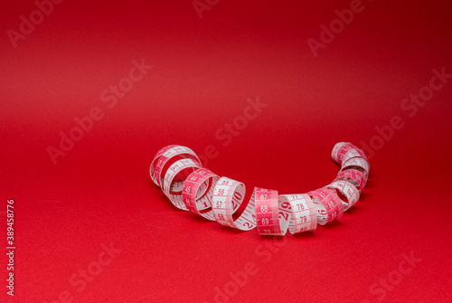 Colorful measuring tape in the form of a spiral on a red background
