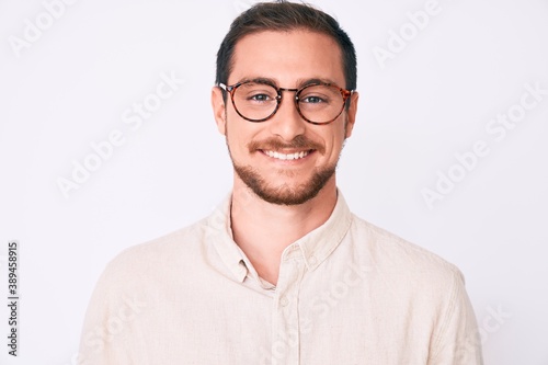 Young handsome man wearing casual clothes and glasses looking positive and happy standing and smiling with a confident smile showing teeth © Krakenimages.com