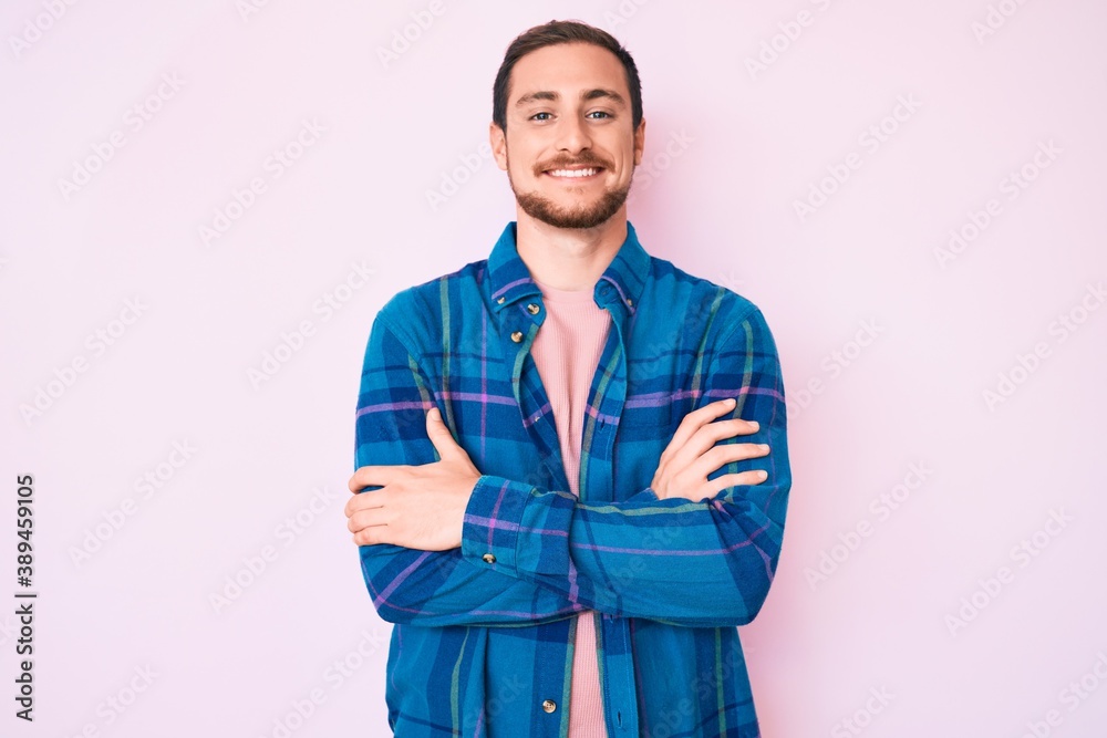 Young handsome man wearing casual clothes happy face smiling with crossed arms looking at the camera. positive person. Young handsome man wearing casual clothes happy face smiling with crossed arms looking at the camera. positive person.
