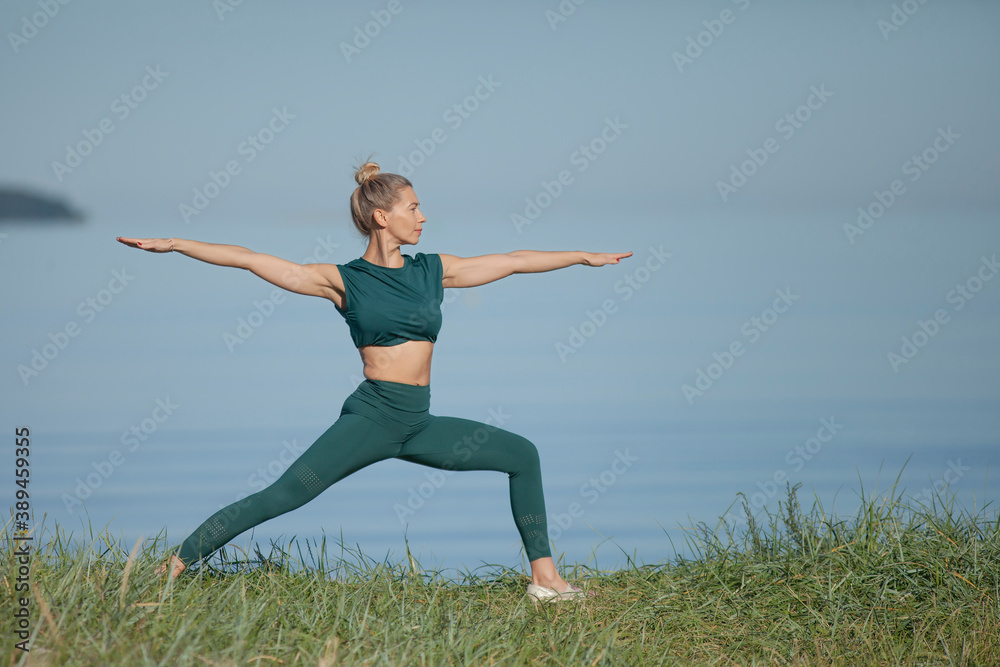 Woman in green sportswear practices yoga by sea Woman in green sportswear practices yoga by sea