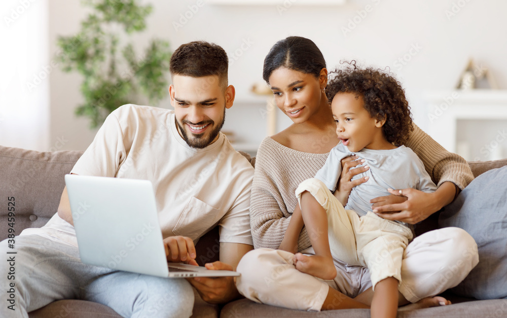 Diverse family using laptop on sofa together.