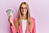 Young blonde woman wearing business style holding japanese yen banknotes looking positive and happy standing and smiling with a confident smile showing teeth