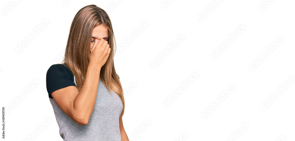 Young blonde woman wearing casual clothes tired rubbing nose and eyes feeling fatigue and headache. stress and frustration concept. Young blonde woman wearing casual clothes tired rubbing nose and eyes feeling fatigue and headache. stress and frustration concept.