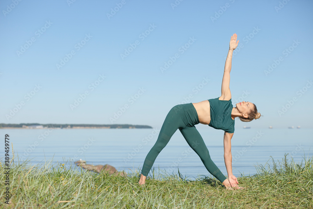 Woman in green sportswear practices yoga by sea Woman in green sportswear practices yoga by sea