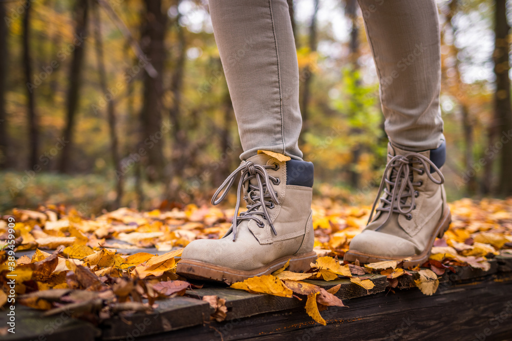 Leather hiking boot on trail in autumn forest. Walking outdoors