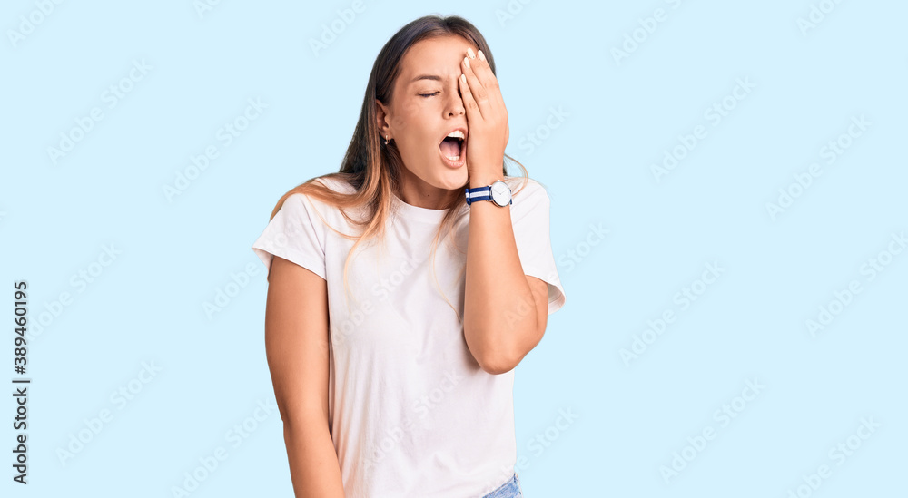Beautiful caucasian woman wearing casual white tshirt yawning tired covering half face, eye and mouth with hand. face hurts in pain. Beautiful caucasian woman wearing casual white tshirt yawning tired covering half face, eye and mouth with hand. face hurts in pain.
