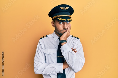 Handsome hispanic man wearing airplane pilot uniform thinking looking tired and bored with depression problems with crossed arms. © Krakenimages.com