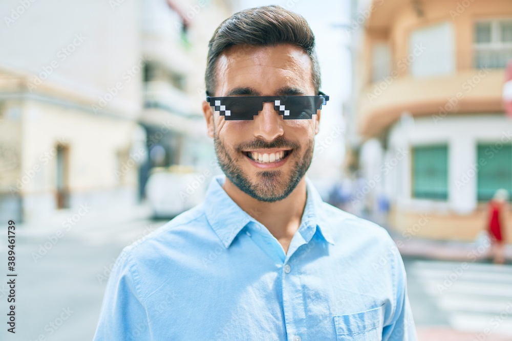 Young hispanic man smiling happy wearing funny sunglasses standing at street of city. Young hispanic man smiling happy wearing funny sunglasses standing at street of city.