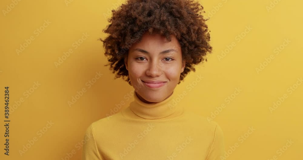 Serious indignant woman with curly hair asks once agains what looks with bewilderment satisfied with heard answer smiles gladfully dressed in casual clothes poses indoor. Slow movement. Emotions