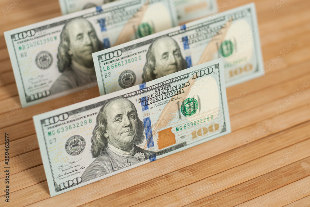 100 Dollars bill and portrait Benjamin Franklin on USA money banknote. Hundred dollar bills on wooden background..