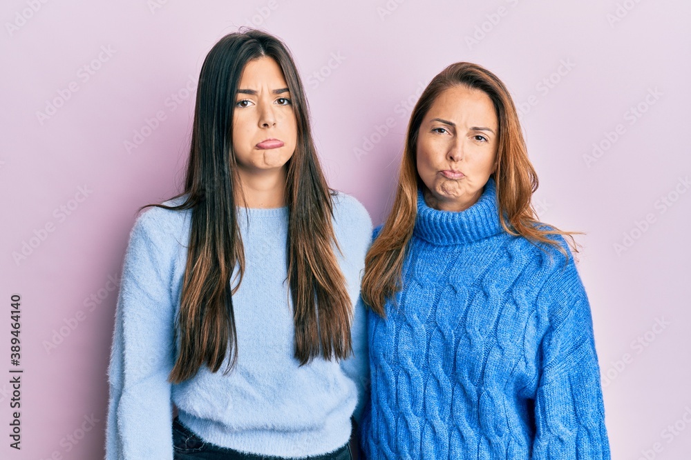 Hispanic family of mother and daughter wearing wool winter sweater depressed and worry for distress, crying angry and afraid. sad expression. Hispanic family of mother and daughter wearing wool winter sweater depressed and worry for distress, crying angry and afraid. sad expression.