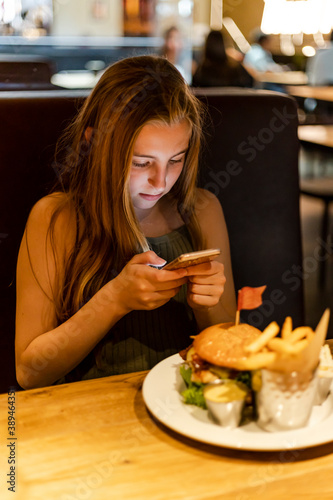 Young girl using phone at restaurant