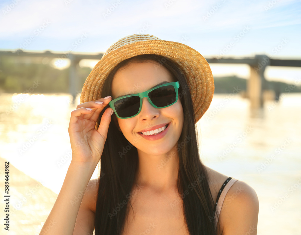 Beautiful young woman wearing stylish sunglasses near river