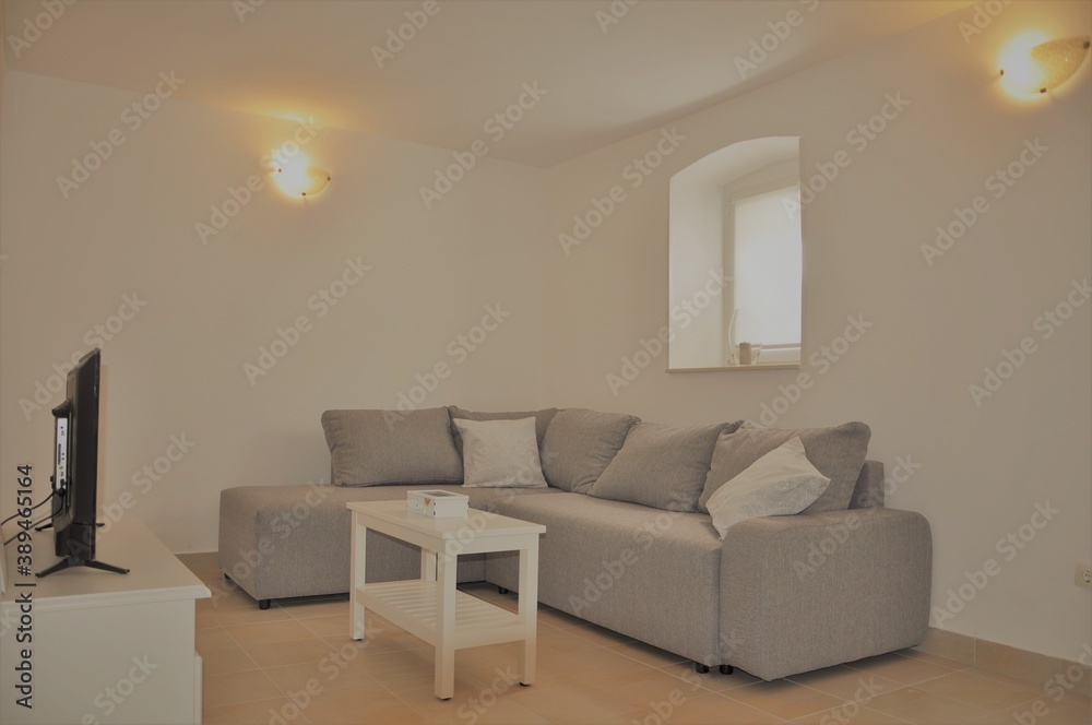 Fototapeta premium Mali Losinj, Croatia 2020.Modern, stylish living room in grey color with window. Interior design of modern grey living room furniture against white wall with a lamps on wall and lots of copy space.