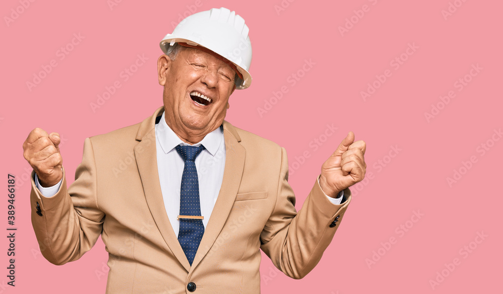 Senior caucasian man wearing architect hardhat very happy and excited doing winner gesture with arms raised, smiling and screaming for success. celebration concept. Senior caucasian man wearing architect hardhat very happy and excited doing winner gesture with arms raised, smiling and screaming for success. celebration concept.