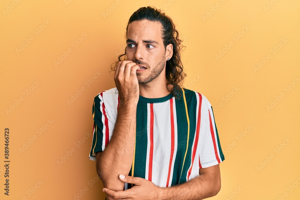 Young handsome man with long hair wearing casual clothes looking stressed and nervous with hands on mouth biting nails. anxiety problem. Young handsome man with long hair wearing casual clothes looking stressed and nervous with hands on mouth biting nails. anxiety problem.