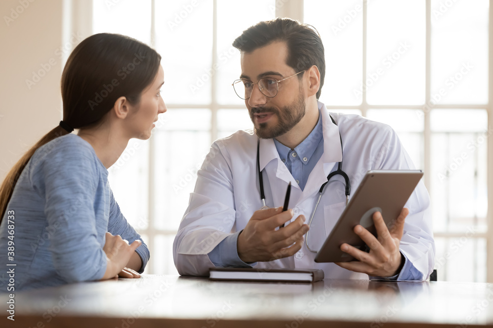 Look at screen, please. Positive capable doc general practitioner demonstrating test results in electronic format or illustrating illness concept to curious patient holding digital tablet pc in hands Look at screen, please. Positive capable doc general practitioner demonstrating test results in electronic format or illustrating illness concept to curious patient holding digital tablet pc in hands