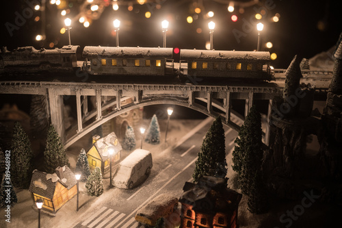 Miniature of winter snowy scene with train on bridge, medieval castle and lantern. Holiday attributes. Night scene. New Year and Christmas concept. Selective focus