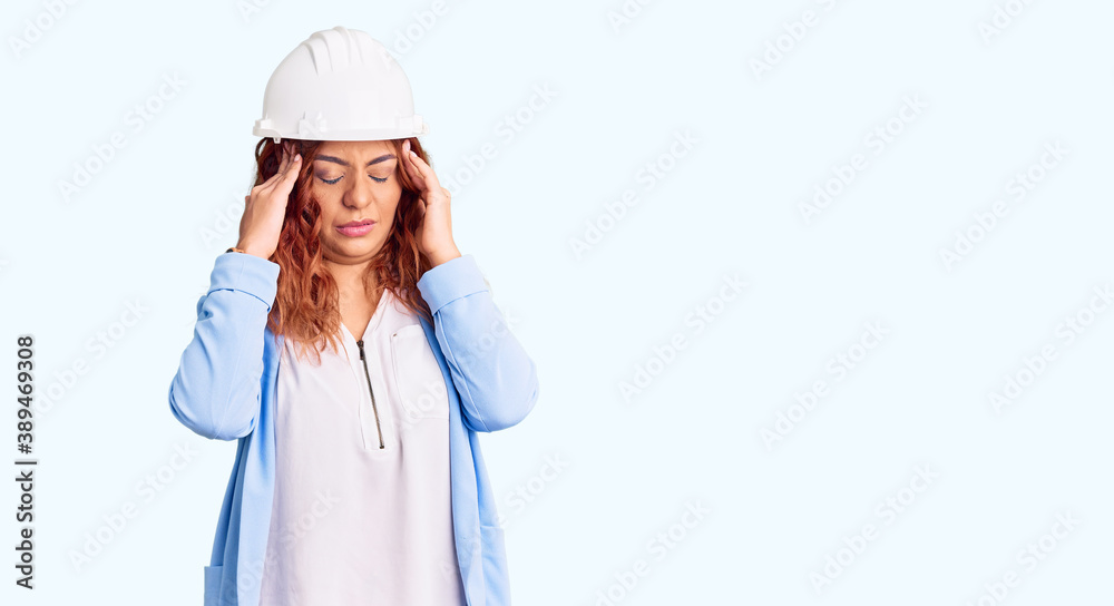 Young latin woman wearing architect hardhat with hand on head for pain in head because stress. suffering migraine. Young latin woman wearing architect hardhat with hand on head for pain in head because stress. suffering migraine.