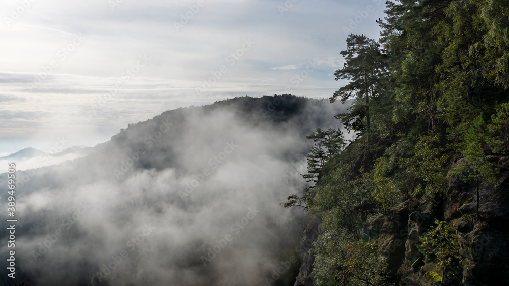Blick in den Morgenstunden von den Affensteinen zum Kleinen Winterberg. Die Sonne schickt ihre ersten wärmenden Strahlen durch den dichten Nebel in die Bergwelt des Nationalparkes Sächsische Schweiz.