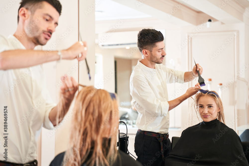 Obraz premium Male hairdresser applying color to female customer