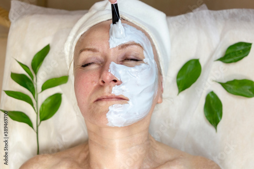 Senior woman having a facial cosmetic mask from professional at spa salon. Anti-aging, facial skin care and luxury lifestyle concept.