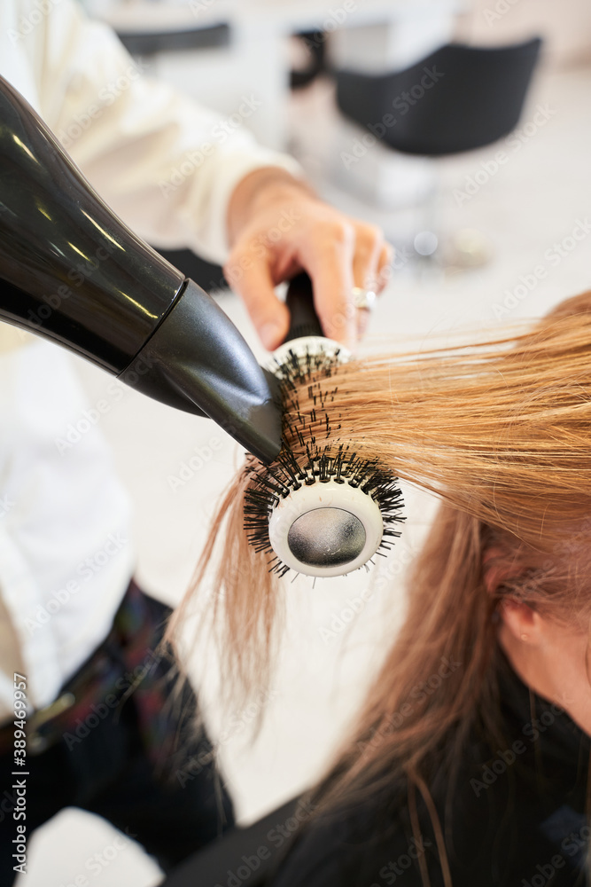 Naklejka premium Hairdresser drying woman's hair with hair dryer