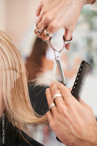 Hairdresser cutting hair for young blonde woman
