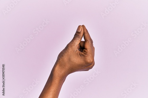 Photos Arm and hand of black middle age woman over pink isolated background holding bla