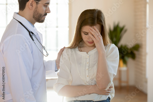 Difficult moment. Attentive compassionate tactful young male doctor supporting comforting stressed depressed frustrated crying female patient hearing bad news of hard diagnosis, death of loved person