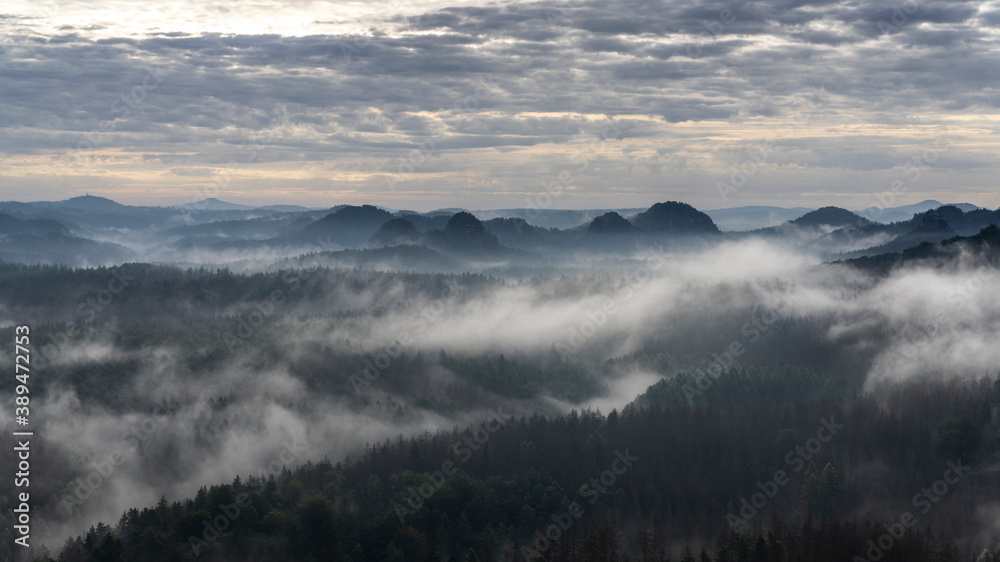 Panoramablick in den Morgenstunden von den Affensteinen zum Kleinen Winterberg. Die Sonne schickt ihre ersten wärmenden Strahlen durch den dichten Nebel in die Bergwelt des Nationalparkes.