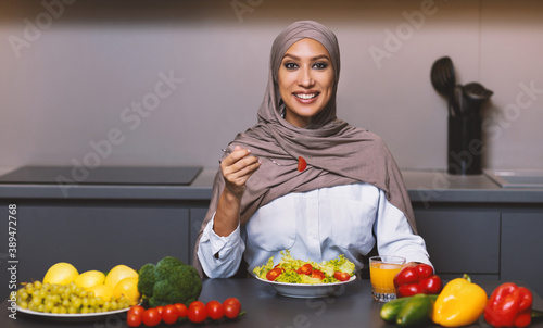Muslim Woman In Hijab Cooking Salad Standing In Modern Kitchen
