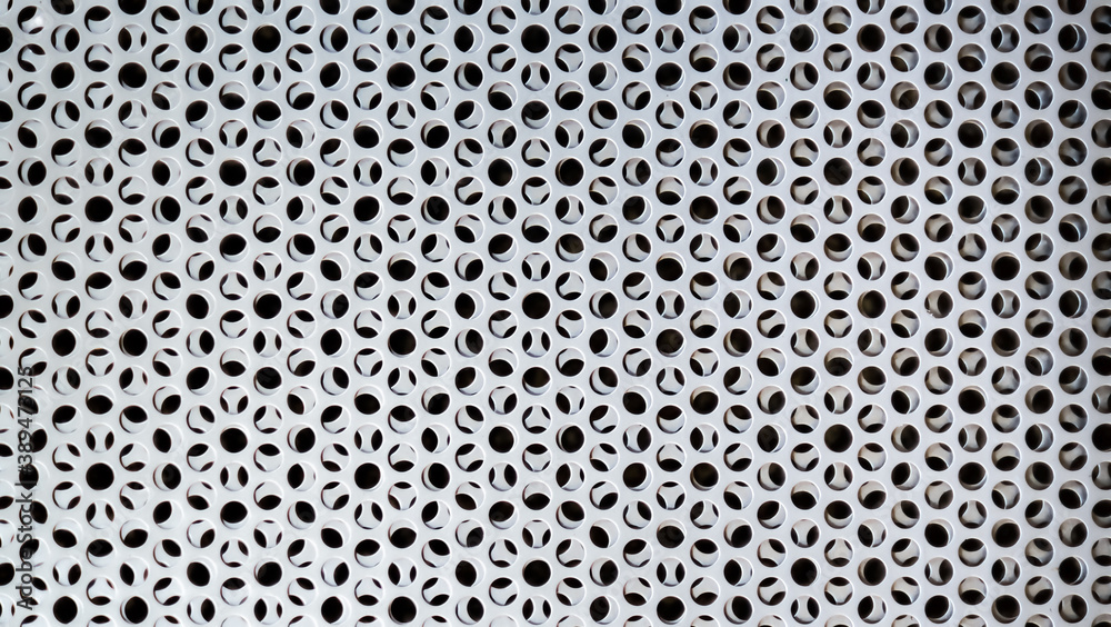 Rusty silver metal background with round holes. Metal texture with holes. Iron gray perforated background. Steel durable material. Circles in the wall. Macro