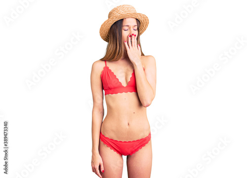 Beautiful brunette young woman wearing bikini bored yawning tired covering mouth with hand. restless and sleepiness.