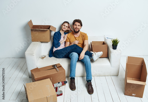 Married couple on a white sofa in the room interior with boxes of communication things © SHOTPRIME STUDIO