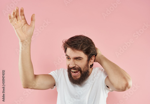 Emotional man on a pink background gesturing with his hands close-up cropped view