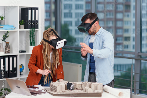 Couple of designers analyse mock-up of future house using augmented reality glasses in modern office
