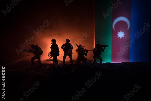 Azeri army concept. Silhouette of armed soldiers against Azerbaijani flag. Creative artwork decoration. Military silhouettes fighting scene dark toned foggy background.