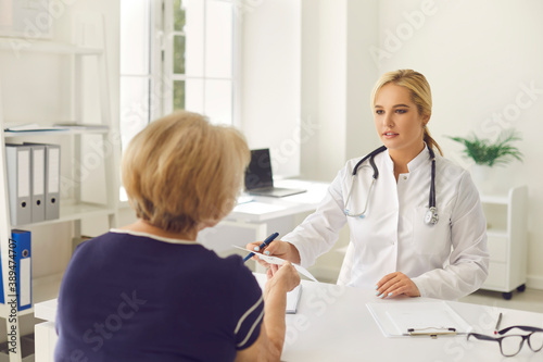 Mature woman discussing her treatment with young physician in modern hospital office