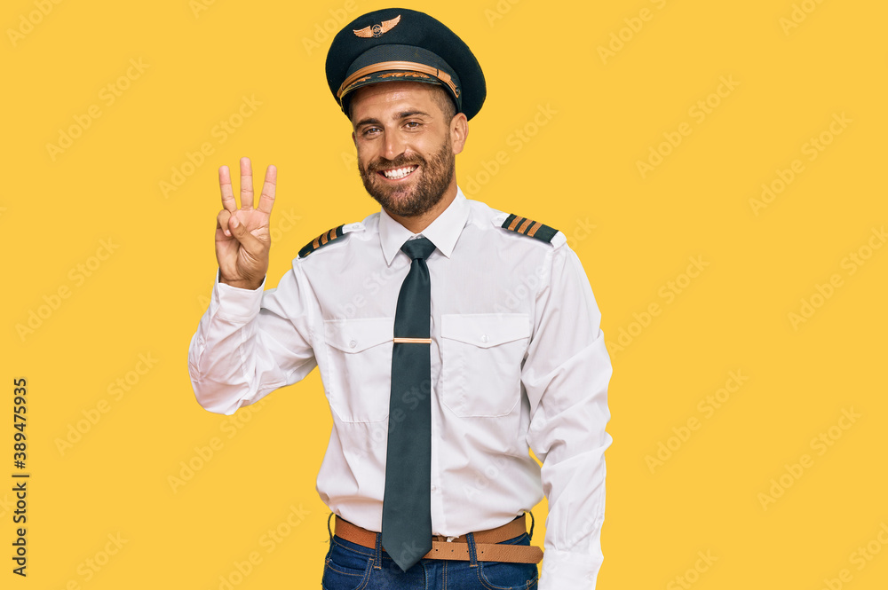 Handsome man with beard wearing airplane pilot uniform showing and pointing up with fingers number three while smiling confident and happy. Handsome man with beard wearing airplane pilot uniform showing and pointing up with fingers number three while smiling confident and happy.