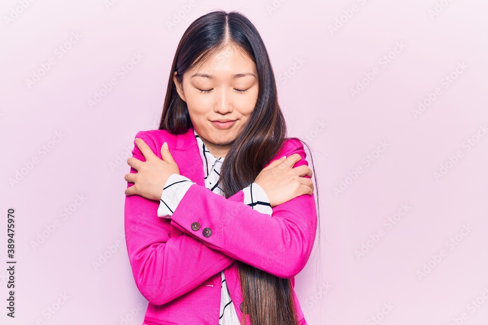 Young beautiful chinese woman wearing elegant clothes hugging oneself happy and positive, smiling confident. self love and self care Young beautiful chinese woman wearing elegant clothes hugging oneself happy and positive, smiling confident. self love and self care