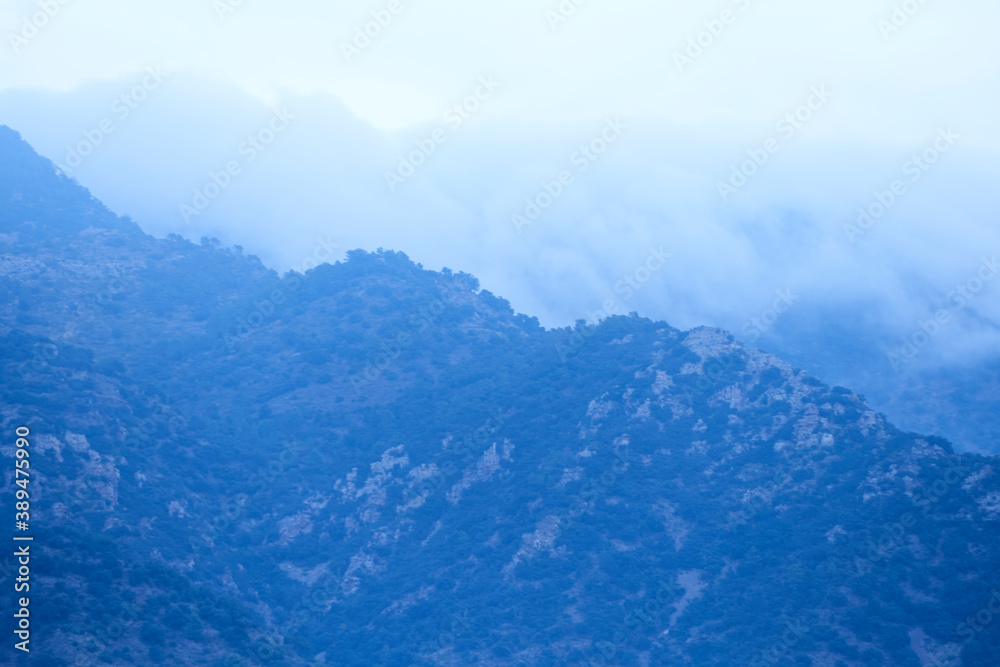 High mountains surrounded by clouds and forests