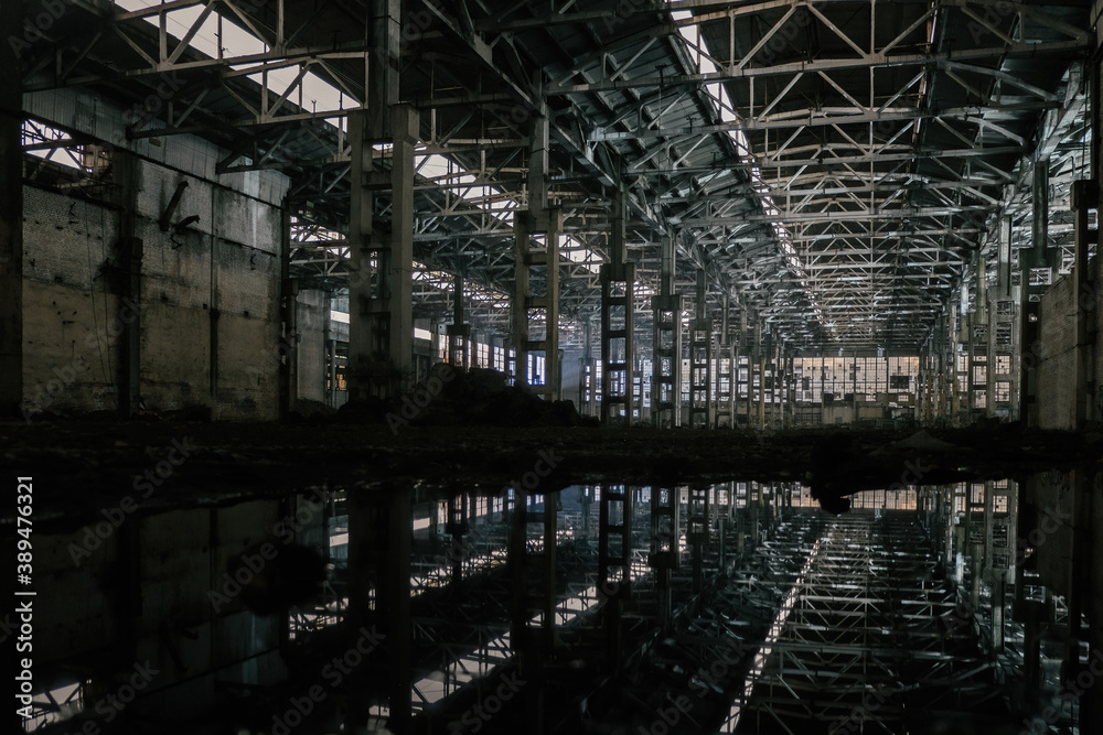 Inside of flooded dirty abandoned ruined industrial building with water reflection