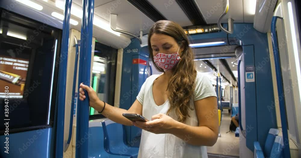 Metro Subway, Montreal, Quebec - August 9, 2020: Young beautiful woman wearing mask standing holding rod and using smartphone while traveling Metro Subway, Montreal, Quebec - August 9, 2020: Young beautiful woman wearing mask standing holding rod and using smartphone while traveling