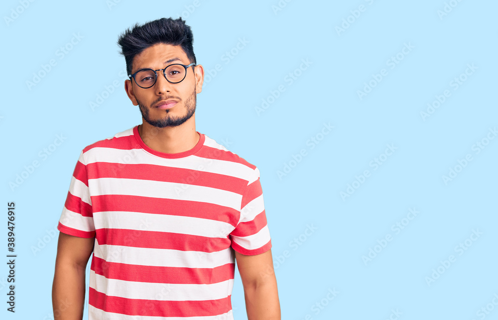 Obraz premium Handsome latin american young man wearing casual clothes and glasses looking sleepy and tired, exhausted for fatigue and hangover, lazy eyes in the morning.