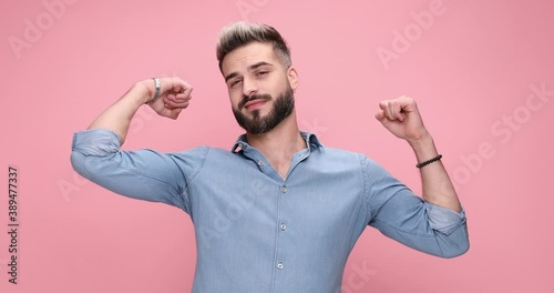 cool casual man flexing his arms, kissing his bicep and being cocky against pink background