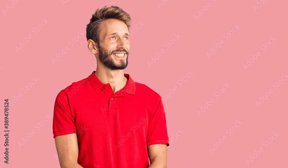 Handsome blond man with beard wearing casual clothes looking away to side with smile on face, natural expression. laughing confident. Handsome blond man with beard wearing casual clothes looking away to side with smile on face, natural expression. laughing confident.