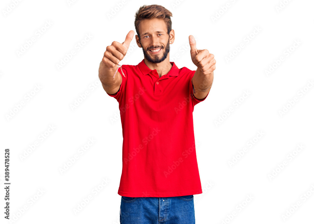 Handsome blond man with beard wearing casual clothes approving doing positive gesture with hand, thumbs up smiling and happy for success. winner gesture.