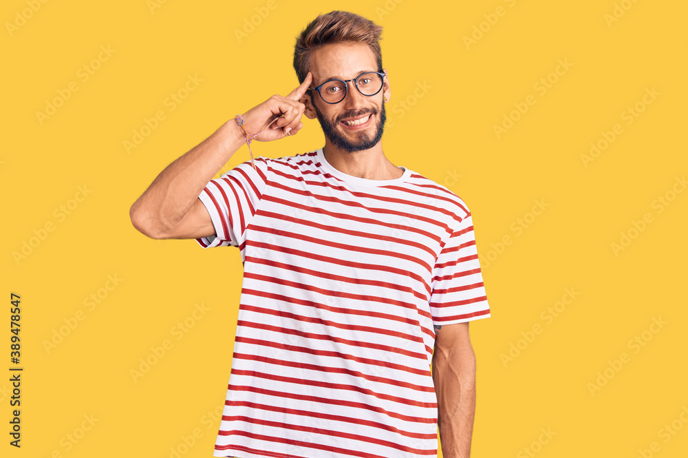 Handsome blond man with beard wearing casual clothes and glasses smiling pointing to head with one finger, great idea or thought, good memory Handsome blond man with beard wearing casual clothes and glasses smiling pointing to head with one finger, great idea or thought, good memory