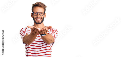 Handsome blond man with beard wearing casual clothes and glasses smiling with hands palms together receiving or giving gesture. hold and protection